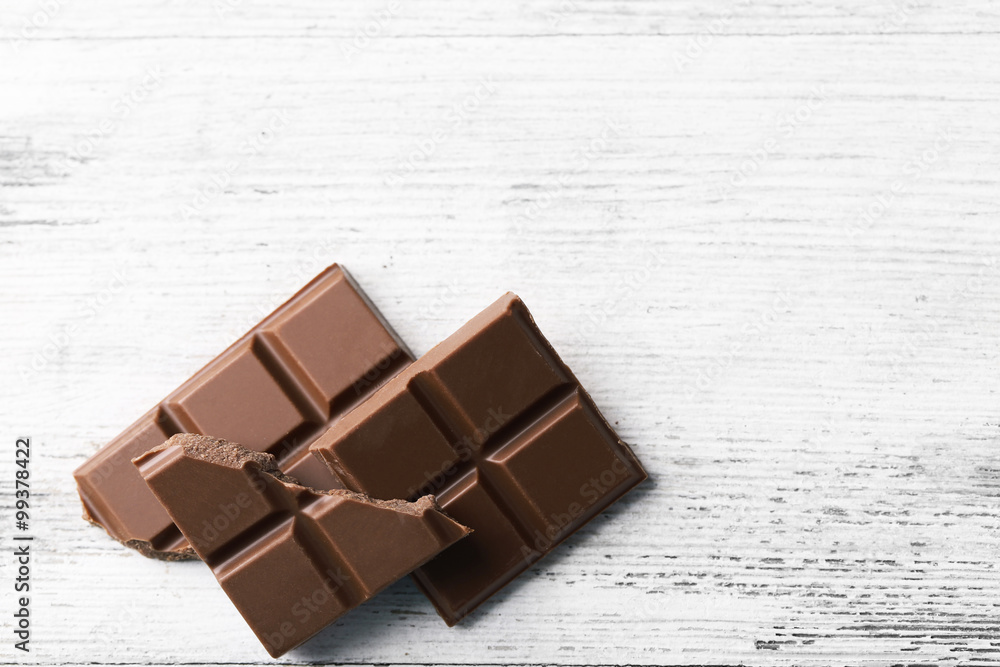 Black chocolate pieces on color wooden background