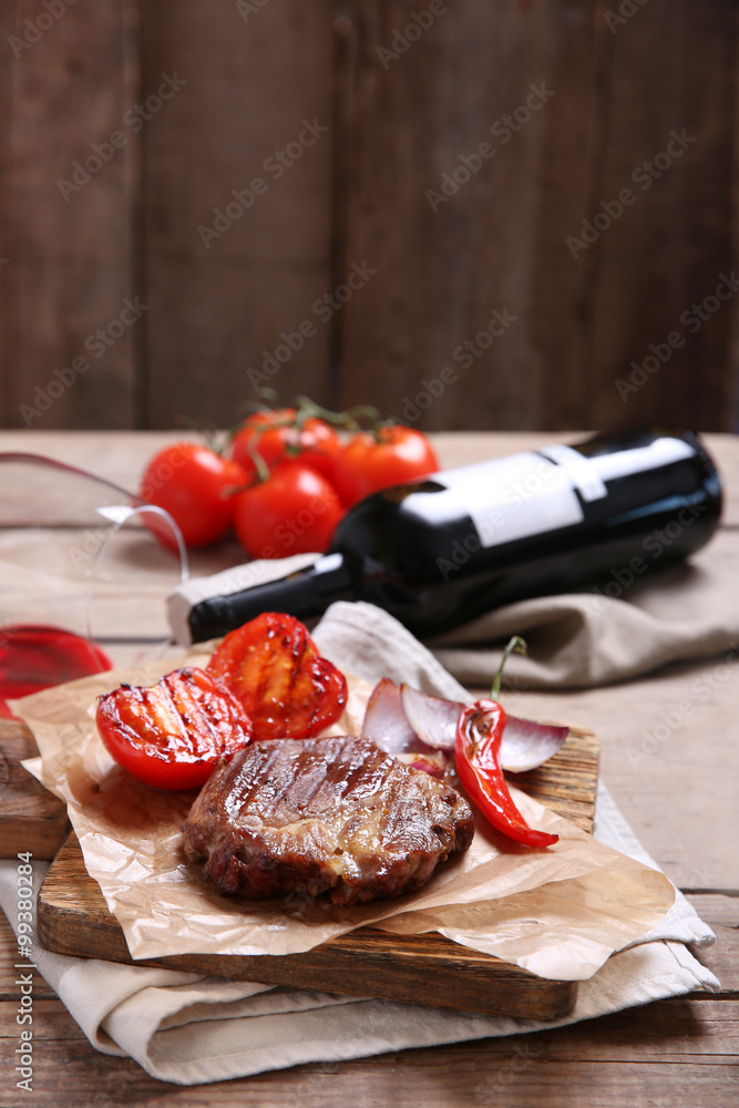 Roasted beef fillet and vegetables on cutting board, on wooden background