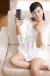 © Blue Jean Images - Asian woman playing with cell phone on a sofa