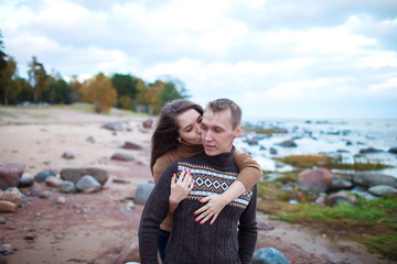 Wall Mural - young couple sitting on a rock on the beach