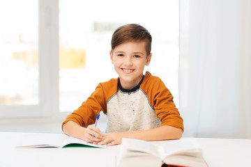 Wall Mural - smiling student boy writing to notebook at home