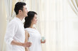 © Blue Jean Images - Happy young couple looking out of window