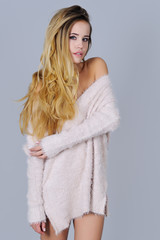 Gorgeous young woman with long beautiful hair posing smiling pink knitted sexy sweater with her shoulders open