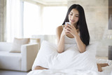 Fototapeta Psy - Young woman using smart phone on bed