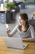 © Blue Jean Images - Young woman using smart phone in office