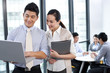 © Blue Jean Images - Businesspeople looking over a laptop with colleagues in the background