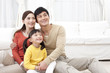© Blue Jean Images - Happy young family sitting on carpet