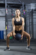 Young woman exercising with medicine ball at gym