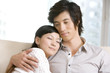 © Blue Jean Images - Asian couple cuddling on a sofa