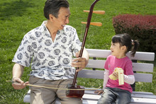 Grandfather Playing Granddaughter Instrument
