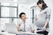 © Blue Jean Images - Pregnant businesswoman working with colleague