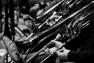 Poster - Trombones in the hands of the musicians in the orchestra in black and white