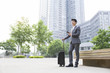© Blue Jean Images - Young businessman holding suitcase and smart phone