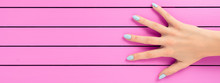 Female Hand With Blue Nails Over Pink Background