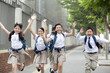 © Blue Jean Images - Smiling students running on footpath