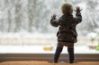 © Gajus - Toddler child standing in front of a big window leaning against