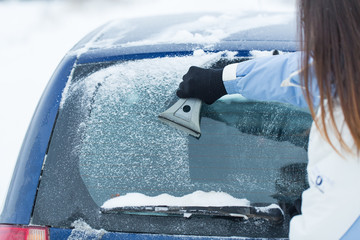 Wall Mural - Woman remove snow from windshield with snow brush.