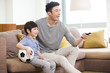 © Blue Jean Images - Father and son watching football on TV