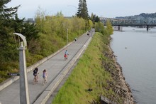 People Biking And Jogging Along The Eastbank Esplanade In Portland, Oregon. Marquam And Hawthorne Bridges In Background.