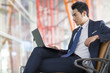 © Blue Jean Images - Young businessman using laptop in airport