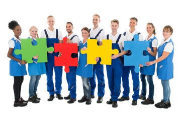 Wall Mural - Confident Janitors Holding Jigsaw Pieces In Row