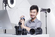 © Blue Jean Images - Photographer cleaning camera lens in studio