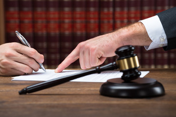 Judge Assisting Client To Sign Legal Document In Courtroom