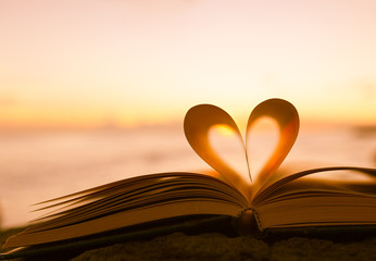 heart from a book page against a beautiful sunset.