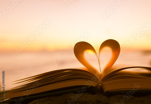 Fotografie, Obraz Heart from a book page against a beautiful sunset.
