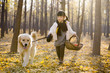 © Blue Jean Images - Little girl walking her dog with a basket in autumn woods