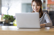© Blue Jean Images - Smiling young woman using a laptop in office