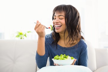 Casual smiling woman eating salad