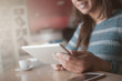 © stokkete - Smiling woman typing on her touch screen tablet
