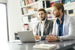 © NDABCREATIVITY - Young businessmen sitting at desk