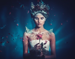 winter beauty fantasy woman portrait. beautiful young model girl and blast of frozen rose.