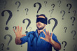 © pathdoc - Portrait business man blindfolded stretching his arms out walking through many questions