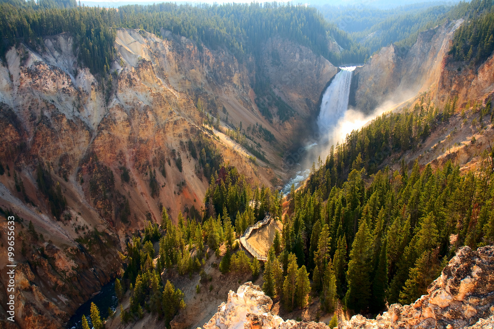 Lower Falls - Sunlight illuminates the spray as the Yellowstone River crashes over the Lower Falls in Yellowstone's Grand Canyon. - obrazy, fototapety, plakaty 