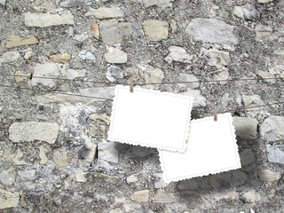 Close-up of two hanged postcards with pegs on old grey stone wall background