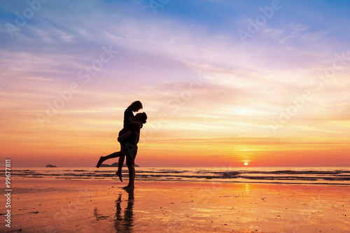 Fotomural Couple kissing on the beach with beautiful sunset in background