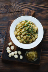 Wall Mural - Above view of gnocchi with basil pesto on a rustic cutting board