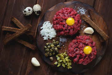 Wall Mural - Above view of beef tartare on a dark rustic wooden background