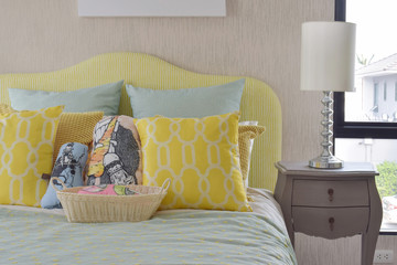 Wall Mural - Yellow and green and pattern pillows on classic style bed and reading lamp on bedside table