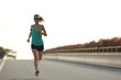young woman runner running on city bridge road