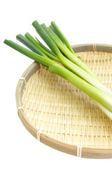 Wall Mural - Japanese bunching onion in bamboo basket on white background