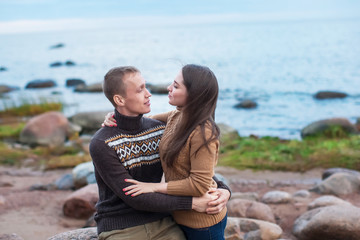 Wall Mural - young couple sitting on a boulder on the beach