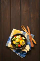 Wall Mural - Baked vegetables of sweet corn, zucchini, cherry tomato with thyme, toasted bread slice and wooden cutlery on the side, photographed on dark wood with natural light