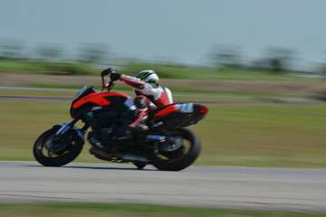 Blurred athletes practicing racing motorcycles on the race track