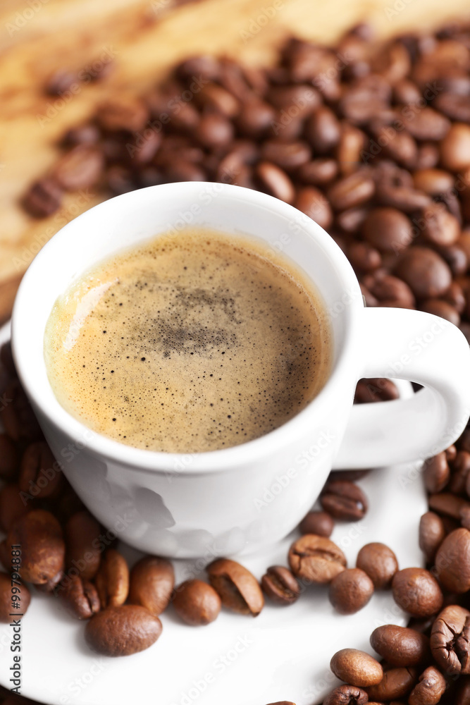 Cup of coffee and coffee grains on wooden table background