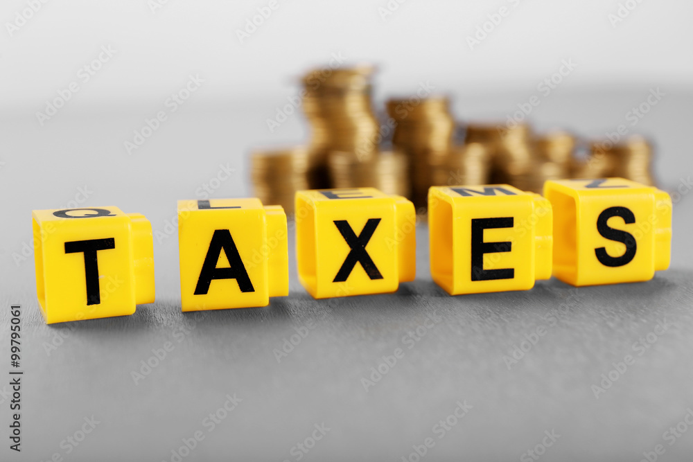 Alphabet TAXES and golden coins on table