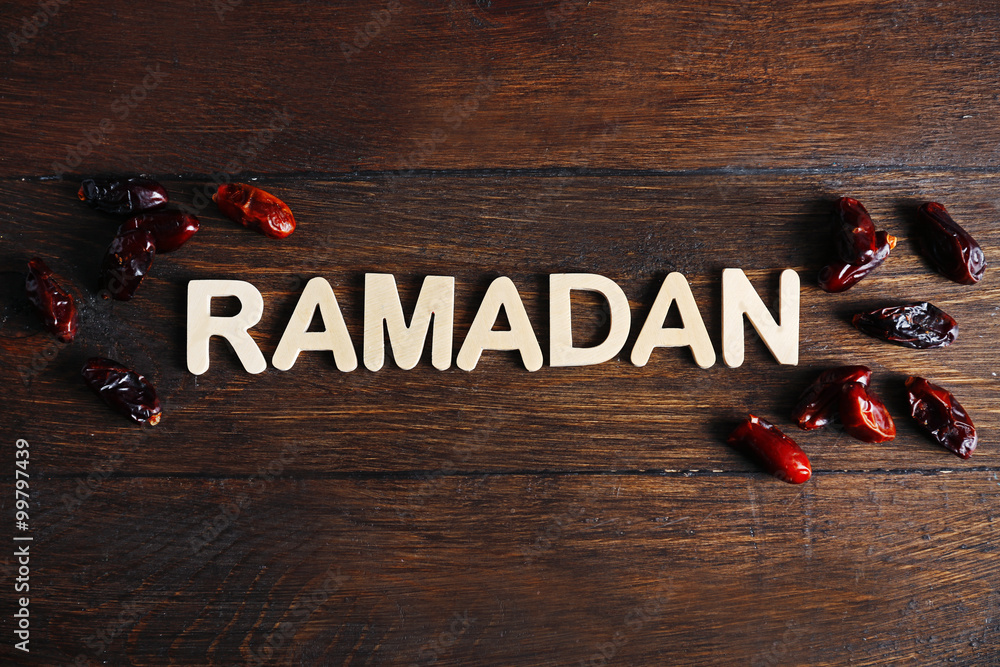 Image of word RAMADAN and dates fruit on wooden background, close up